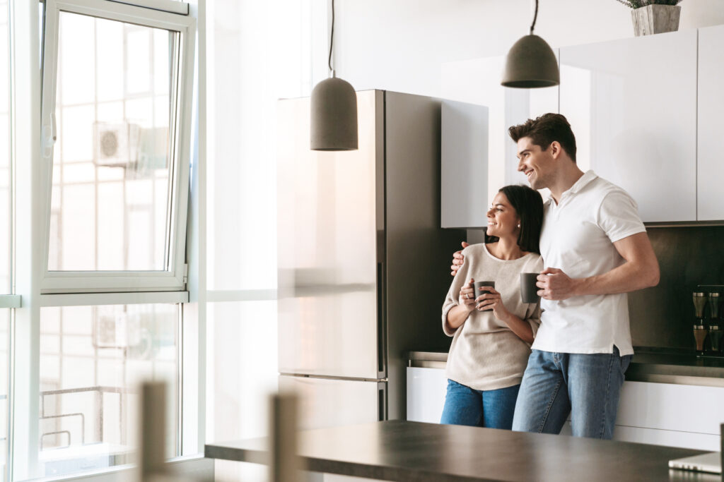 Young couple stood in a kitchen next to a fridge freezer